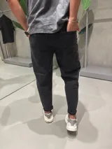 Jean de corte slouchy en color negro con efecto gastado. Presenta un diseño de tiro medio, bolsillos laterales y traseros, con un ajuste ligeramente holgado en la parte superior que se estrecha hacia el tobillo.