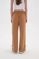 Pantalon deportivo de corte recto y tiro medio, color beige oscuro. Presenta una banda lateral en tono crema y aberturas ajustables con cordones en los tobillos. Cuenta con cintura elástica.