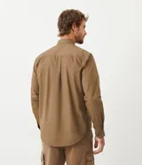 Camisa de manga larga confeccionada en sarga de algodón, con cuello clásico, cierre frontal abotonado y dos bolsillos frontales con solapa y botón.