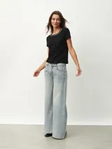 Remera negra de corte clásico con cuello redondo ribeteado con pequeñas perlas blancas.