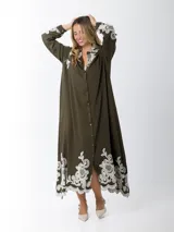 Maxi vestido camisero de lino blanco con bordados en tono beige en mangas y ruedo. Presenta cuello camisero, botones frontales y mangas largas.