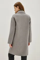 Tapado negro de corte recto y largo medio, con solapas clásicas, cierre frontal de un botón y bolsillos laterales amplios.