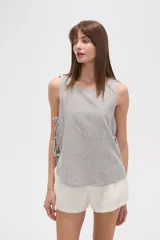 Blusa sin mangas de calce holgado, confeccionada en viscosa con estampado de rayas verticales. Presenta cuello redondo y laterales abiertos ajustables mediante cordones.