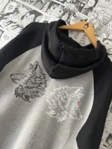 Canguro gris con capucha y mangas largas negras. Estampado en el frente con diseño de manos en blanco y negro.