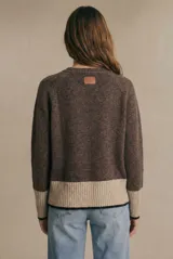 Sweater de punto color marrón oscuro y beige, con diseño de rombos en el parte frontal. Tiene cuello redondo y mangas largas con puños acanalados.