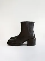 Bota corta de cuero negro con punta cuadrada y taco bloque texturizado. Presenta cierre lateral y costura central en el empeine.