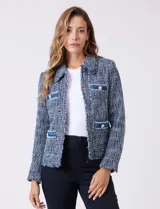 Chaqueta de tweed azul con cuello a la base, abertura central y bolsillos delanteros. Presenta detalles de denim en los bolsillos y puños, con botones perlados. Terminación desflecada y forro interno.