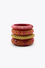 Pack de cuatro pulseras rígidas de madera recubiertas con rafia tejida en tonos rosados, naranjas y verde oliva.