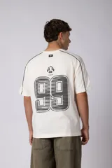 Remera de algodón color blanco con corte regular, cuello redondo y mangas cortas. Presenta detalles de líneas finas negras en los hombros y estampado gráfico frontal con tipografía y logotipos en color negro.