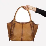 Cartera al hombro color marrón de cuero con doble asa, cierre superior y detalles de hebillas y cierres en el frente.