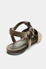 Sandalia plana estilo cangrejera con acabado efecto terciopelo en color marrón. Presenta diseño de tiras cruzadas, cierre mediante hebilla metálica lateral y punta redonda.