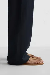 Sandalia minimalista de cuero negro, con tira delgada en el empeine y suela plana.