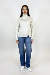 Polera de cuello alto en color beige, confeccionada en tejido de punto suave, con corte recto y detalle de tajo lateral en el ruedo.