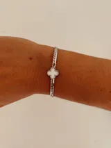 Pulsera de acero quirúrgico en tono plateado con cadena de eslabones tipo ratón y dije central en forma de trébol con centro blanco.