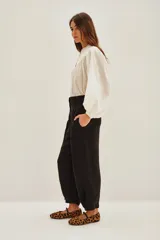 Pantalón sastrero de tiro alto, color blanco, confeccionado en cupro y viscosa. Presenta pinzas delanteras, bolsillos y ajuste elástico en el tobillo.