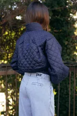 Campera acolchada de color azul marino, con diseño de rombos, cuello tipo chal y cierre frontal con botones grandes al tono. Presenta puños y ruedo acanalados, y bolsillos laterales.