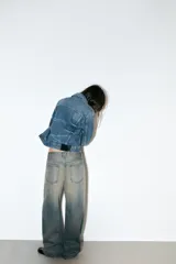 Jeans de tiro bajo con corte baggy y silueta barrel. Presenta diseño de cinco bolsillos, trabillas para cinturón y cierre frontal con cremallera y botón metálico. Confeccionado en denim con efecto de lavado desgastado.