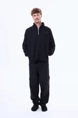 Pantalón cargo de denim negro con corte holgado, bolsillos laterales con solapa y cierre frontal con botón.