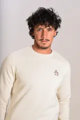 Buzo de cuello redondo en color beige claro, confeccionado en tejido de algodón. Presenta un diseño minimalista con el logo bordado de la marca en el pecho y puños acanalados.