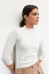 Polera de algodón color blanco, con cuello alto y mangas tres cuartos. Presenta un diseño ajustado al cuerpo con costuras decorativas en las sisas.
