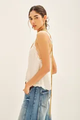 Top negro de viscosa con breteles finos y escote en V con puntilla. Presenta apliques de tachas termo adhesivas en el frente.