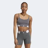 Bralette deportivo Adidas Hyperglam color gris oscuro con tirantes finos ajustables. Presenta detalles de costuras curvas y una banda elástica inferior en color blanco con el logo de Adidas.