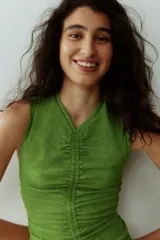 Vestido largo sin mangas de color verde, confeccionado en punto con efecto arrugado. Presenta escote en V con fruncido central en la parte delantera, costuras drapeadas y falda con vuelo con corte fruncido bajo las caderas.
