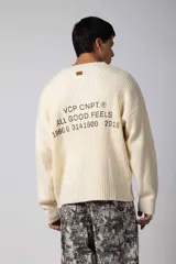 Sweater de punto acanalado con diseño de calce relajado, cuello redondo y mangas largas. Presenta una estampa gráfica pequeña en el centro del pecho y un parche con logo en el puño.