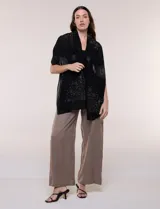 Pashmina rectangular de gasa semitransparente negra, con apliques de microstrass brillantes que forman motivos estelares. Tejido fluido de caída ligera.