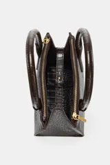 Bolso tipo mini city color marrón oscuro con textura de relieve de cocodrilo. Tiene doble asa de mano y una bandolera extraíble. Cuenta con compartimentos interiores con cremalleras metálicas.