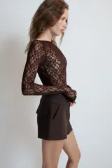 Bermudas de tiro medio color negro, con cintura ancha, bolsillos delanteros y cierre frontal con cremallera y ganchos metálicos.