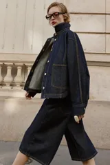 Bermuda de tiro alto confeccionada en denim azul oscuro, con diseño de pernera ancha, cinco bolsillos y cierre frontal con cremallera y botón.