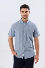 Camisa de manga corta confeccionada en mezcla de lino y algodón, con estampado de cuadros pequeños en tonos azules. Presenta cuello camisero con botones, cierre frontal abotonado, bolsillo aplicado en el pecho y dobladillo redondeado.