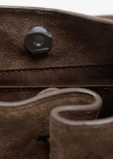 Bolso de mano tipo bandolera confeccionado en piel bovina de color marrón. Cuenta con un diseño estructurado, solapa frontal con detalle de trabilla y hebilla metálica, y asa corta para llevar al hombro o en la mano.