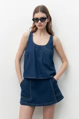 Blusa sin mangas de jean azul oscuro con escote redondo y bolsillo de parche en el pecho.