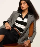 Blazer de tweed gris con diseño de espiga, doble botonadura, solapas de muesca, bolsillos cargo frontales y corte clásico.