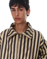 Chaqueta corta de gabardina de algodón a rayas verticales en tonos beige y negro. Tiene cuello alto, cierre metálico frontal, bolsillos laterales y está totalmente forrada.