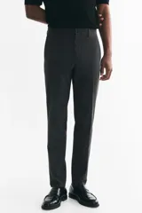 Pantalón sastrero gris oscuro con corte slim fit, pliegues frontales y raya marcada en las piernas. Cuenta con cierre de botón y bolsillos laterales.