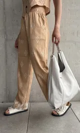Pantalón beige de corte recto con estampado de rombos blancos y cintura elastizada.