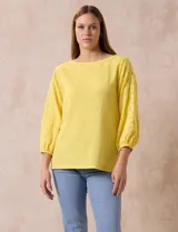 Blusa amarilla texturada con escote redondo y mangas 3/4 con puño elastizado. Aplique de broderie en escote y mangas. Marca Ruby Rd.