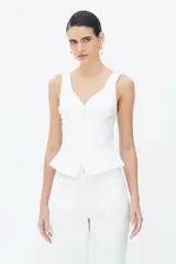 Blusa de algodón color blanco roto con tirantes anchos, escote en V y corte en el busto. Cuenta con cierre frontal de botones forrados y bajo evasé.