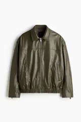 Campera estilo bomber de tejido revestido color verde militar, con cuello, cierre frontal metálico, bolsillos laterales insertados, cierre en los puños y elástico fruncido en el bajo.