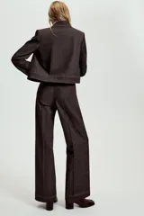 Pantalón de tiro medio en denim oscuro con costuras a contraste. Presenta corte recto, bolsillos delanteros, trabillas en la cintura y cierre frontal con cremallera y ganchos metálicos.