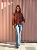 Camisa de manga larga color marrón chocolate, con cuello alto y detalles de volados a lo largo de la botonadura frontal.
