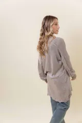 Cardigan tejido liviano color beige con efecto brillante y calados en las mangas. Diseño abierto y corte relajado.