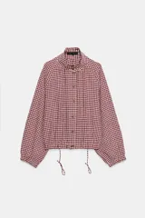 Chaqueta de manga larga con estampado de cuadros vichy en tonos marrón y blanco, cuello camisero, cierre frontal con botones y bajo ajustable con cordón.