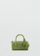 Bolso de mano cilíndrico de cuero gamuzado color verde, con dos asas cortas y detalle de lazo decorativo en un lateral. Cuenta con cierre superior de cremallera.