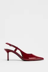 Zapato de tacón destalonado con acabado efecto acharolado, diseño de punta fina y cierre mediante tira trasera con hebilla metálica ajustable.