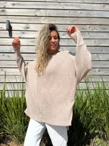 Sweater de punto en color beige, con diseño oversize, cuello redondo, mangas largas con puños acanalados y tajos laterales en el ruedo.