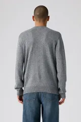 Sweater de tejido de punto gris jaspeado, con cuello redondo, mangas largas y puños y ruedo acanalados. Presenta el logo de la marca bordado en pequeño en el pecho.